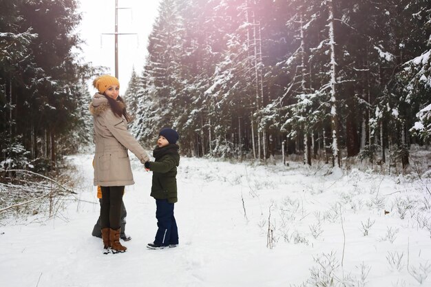 Famiglia felice che gioca e ride in inverno all'aperto nella neve. Giornata invernale del parco cittadino.