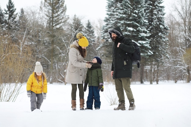 Famiglia felice che gioca e ride in inverno all'aperto nella neve. Giornata invernale del parco cittadino.