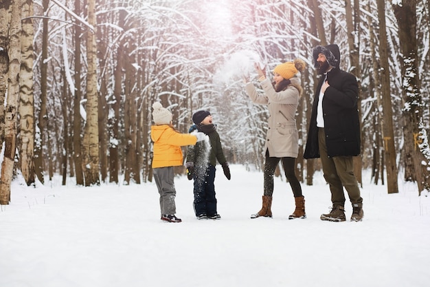 Famiglia felice che gioca e ride in inverno all'aperto nella neve. Giornata invernale del parco cittadino.