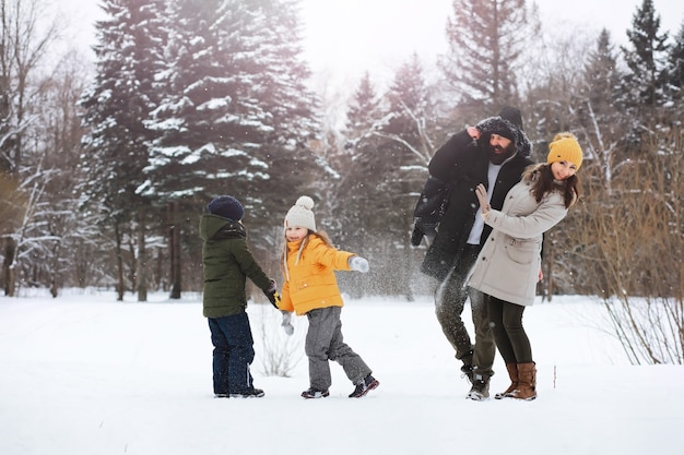 Famiglia felice che gioca e ride in inverno all'aperto nella neve. Giornata invernale del parco cittadino.