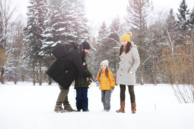 Famiglia felice che gioca e ride in inverno all'aperto nella neve. Giornata invernale del parco cittadino.