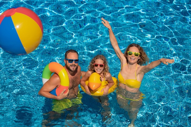 Famiglia felice che gioca nella piscina all'aperto Persone che si divertono durante le vacanze estive Concetto di stile di vita sano