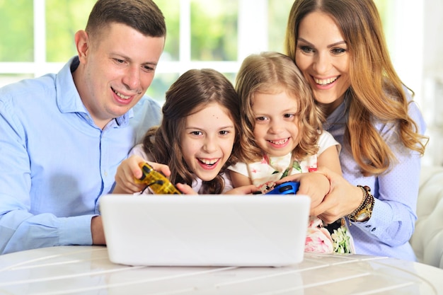 Famiglia felice che gioca sul computer portatile al tavolo