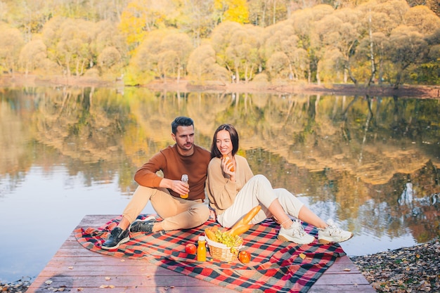 Famiglia felice che gode del giorno di autunno sul lago sul picnic