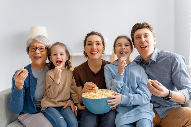 Famiglia felice che guarda film TV con proiettore con popcorn a casa