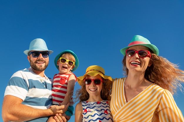 Famiglia felice che ha divertimento contro il cielo blu. Madre, padre, figlia e figlio in vacanza estiva