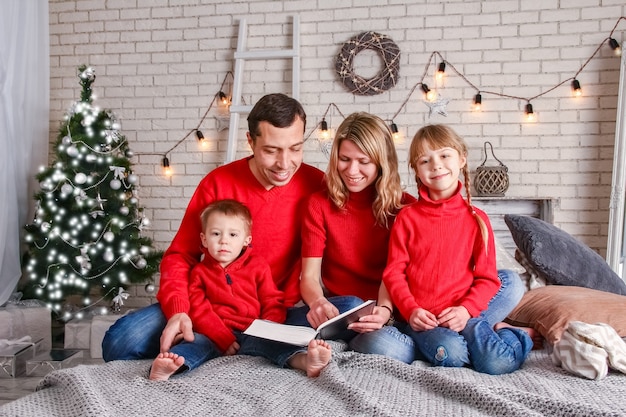 Famiglia felice che legge un libro a casa a Natale