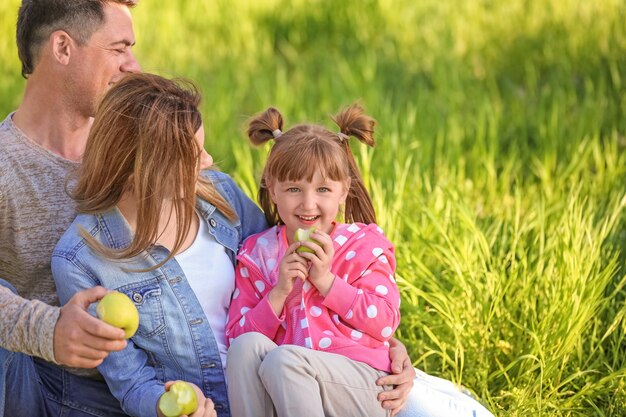 Famiglia felice che mangia mele nel parco