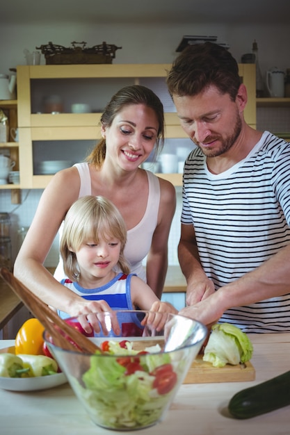 Famiglia felice che prepara insalata nella cucina