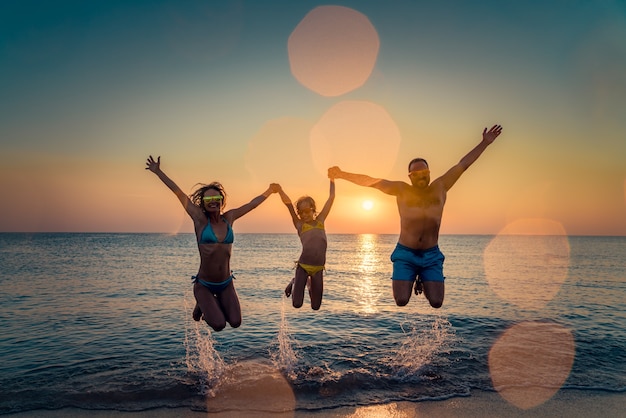 Famiglia felice che salta nel mare Persone che si divertono all'aperto Vacanze estive e concetto di stile di vita sano