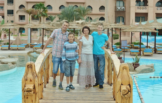 Famiglia felice che si diverte al resort tropicale vicino alla piscina.