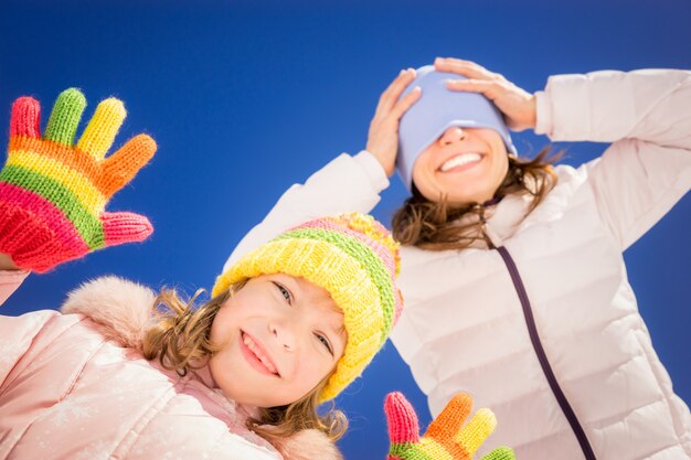 Famiglia felice che si diverte all'aperto in inverno sullo sfondo del cielo blu