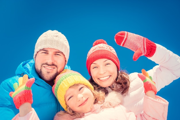 Famiglia felice che si diverte all'aperto in inverno sullo sfondo del cielo blu