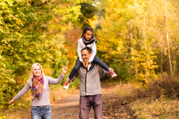 Famiglia felice che si diverte all'aperto nel parco autunnale su sfondo di foglie sfocate