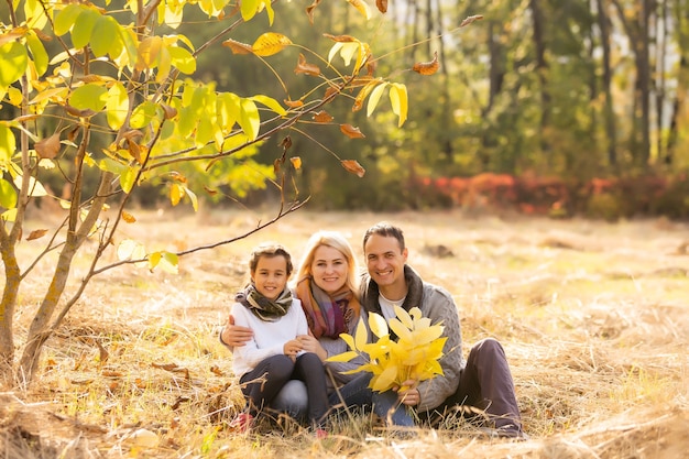 Famiglia felice che si diverte all'aperto nel parco autunnale su sfondo di foglie sfocate