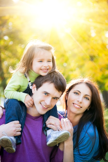 Famiglia felice che si diverte all'aperto nel parco autunnale su sfondo dorato e soleggiato