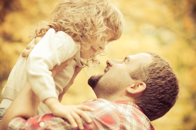 Famiglia felice che si diverte all'aperto nel parco autunnale sullo sfondo giallo delle foglie sfocate