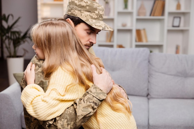 Famiglia felice che si diverte di una riunione militare Padre in uniforme che abbraccia sua figlia nel soggiorno