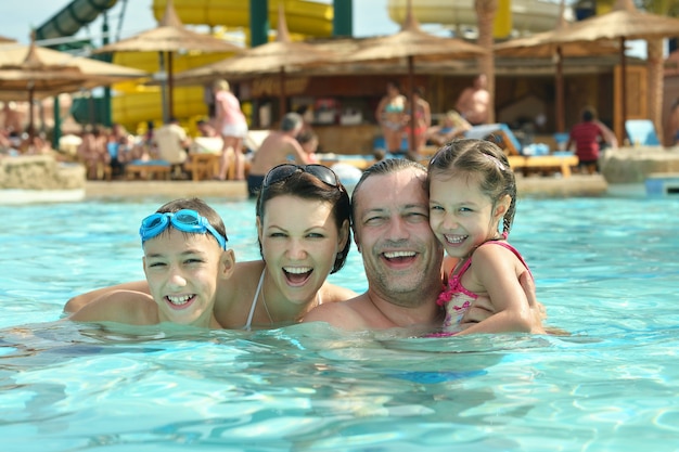 Famiglia felice che si diverte in piscina con il pollice in alto