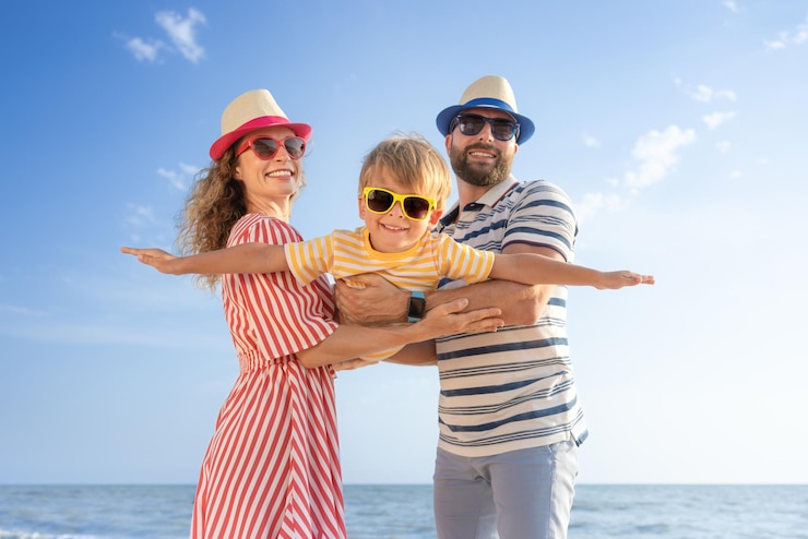 Foto famiglia felice che si diverte sulla spiaggia madre e padre che tengono il figlio contro il blu del mare e dello sfondo del cielo concetto di vacanza estiva