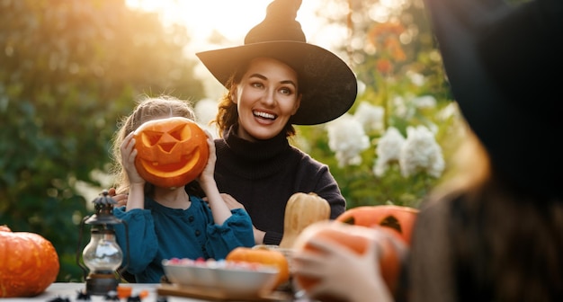 Famiglia felice che si prepara per Halloween Madre e figli che scolpiscono zucche nel cortile