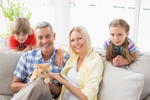 Famiglia felice che si siede con il gatto sul sofà a casa