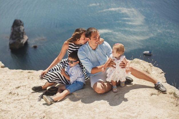 Famiglia felice che si siede in montagna sul mare