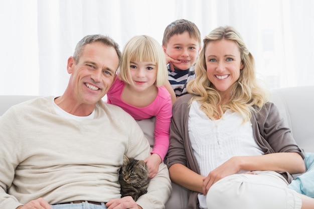 Famiglia felice che si siede insieme con il gattino dell&#39;animale domestico