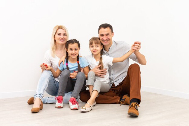 Famiglia felice che si siede sul pavimento di legno. Padre, madre e figlio si divertono insieme. Giorno del trasloco, nuovo concetto di casa