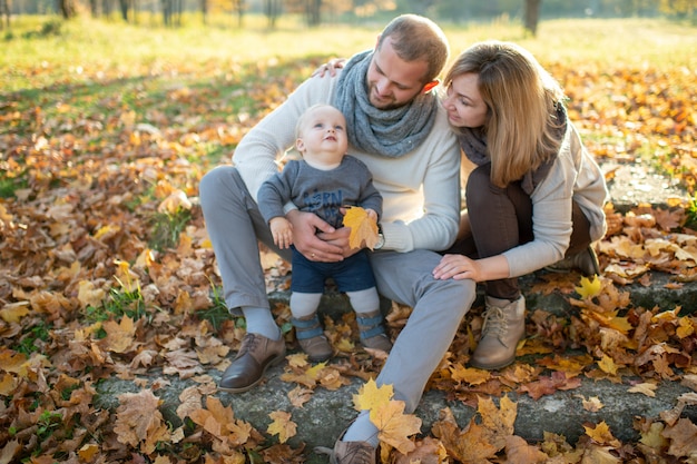 Famiglia felice che si siede sulle scale con le foglie di autunno