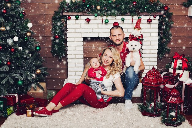 Famiglia felice che si siede vicino al camino con il piccolo figlio e cane sveglio e sorridere