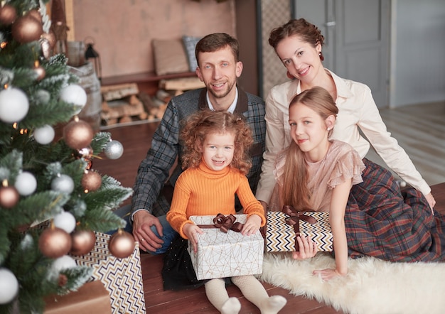 Famiglia felice che si siede vicino all'albero di Natale nell'accogliente soggiorno.