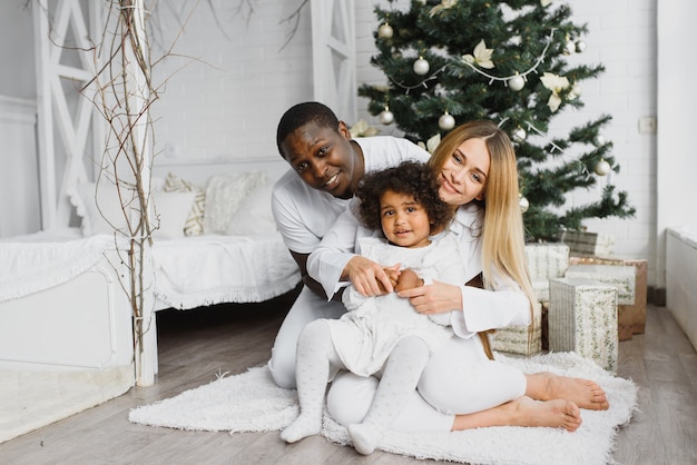 Famiglia felice che si siede vicino all'albero di Natale