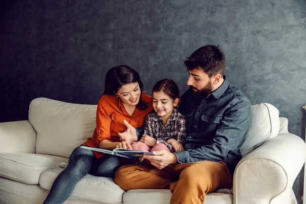 Famiglia felice che si siedono insieme e che hanno tempo di qualità insieme. Il padre sta leggendo una favola alla sua amata figlia.