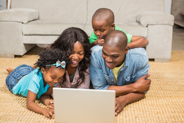 Famiglia felice che si trova sul pavimento per mezzo del computer portatile