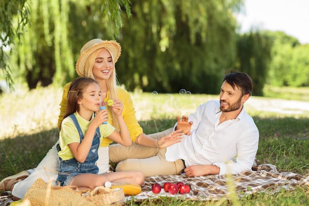 Famiglia felice che soffia bolle nel parco estivo