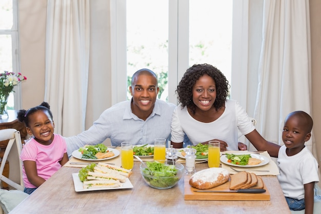 Famiglia felice che sorride alla macchina fotografica a pranzo