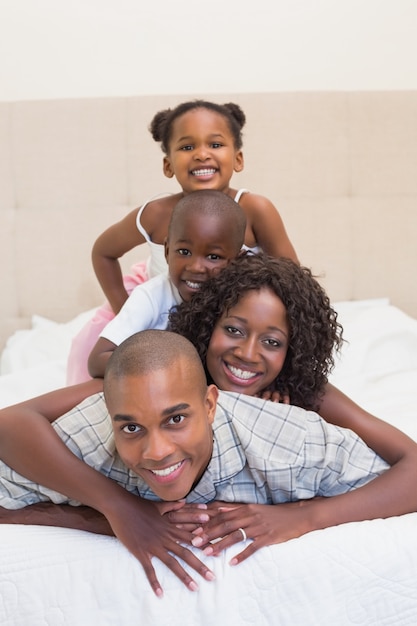 Famiglia felice che sorride insieme alla macchina fotografica sul letto