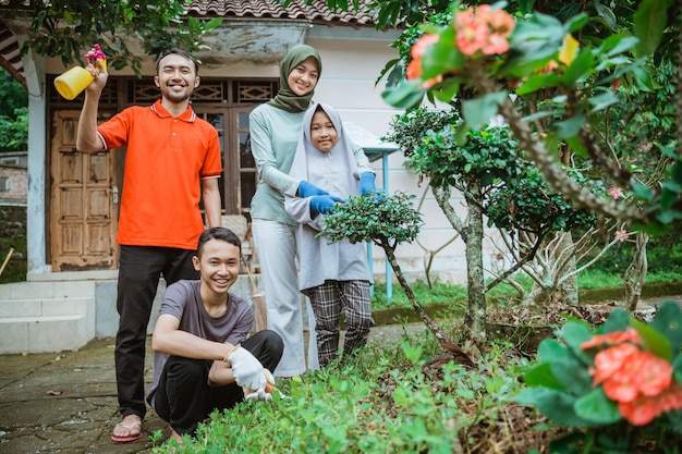 Famiglia felice che sorride stando in piedi nel cortile mentre fa giardinaggio