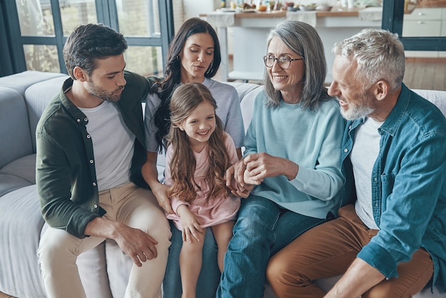 Famiglia felice che trascorre del tempo insieme e sorride mentre è seduta sul divano di casa