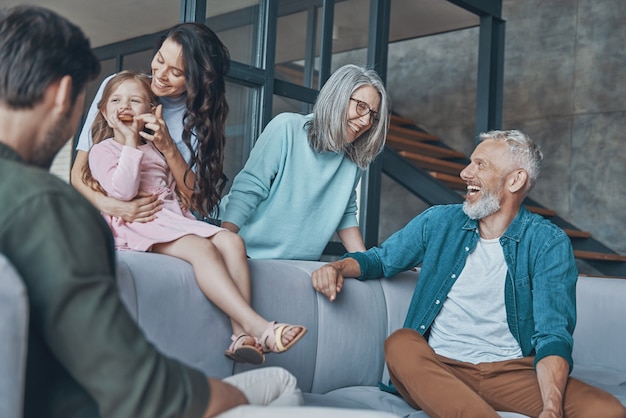 Famiglia felice che trascorre del tempo insieme e sorride mentre è seduta sul divano di casa