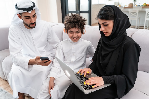 Famiglia felice che trascorre del tempo insieme. I genitori arabi e il loro figlio giocano e fanno diverse attività a casa