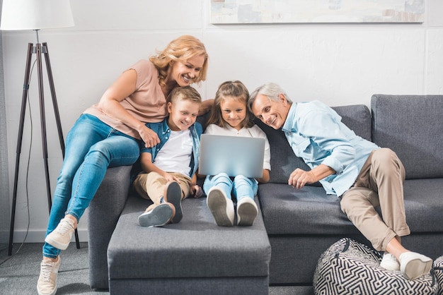 famiglia felice che usa il laptop mentre è seduto sul divano di casa