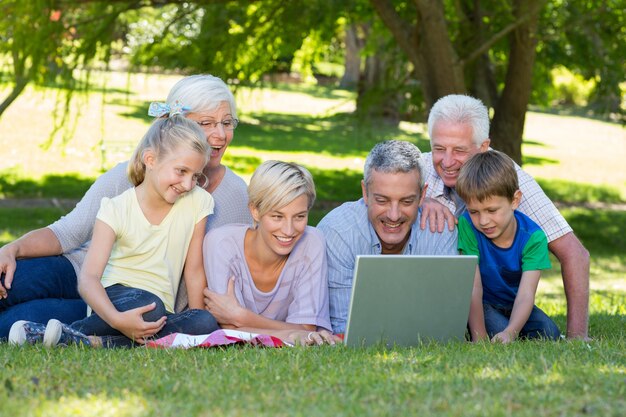 Famiglia felice che utilizza computer portatile nel parco