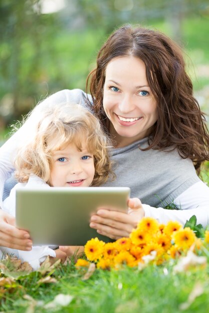 Famiglia felice che utilizza tablet PC su sfondo verde primavera