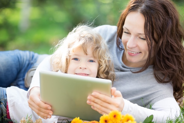 Famiglia felice che utilizza tablet PC su sfondo verde primavera