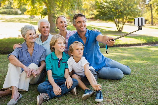 Famiglia felice che utilizza un bastone del selfie nel parco