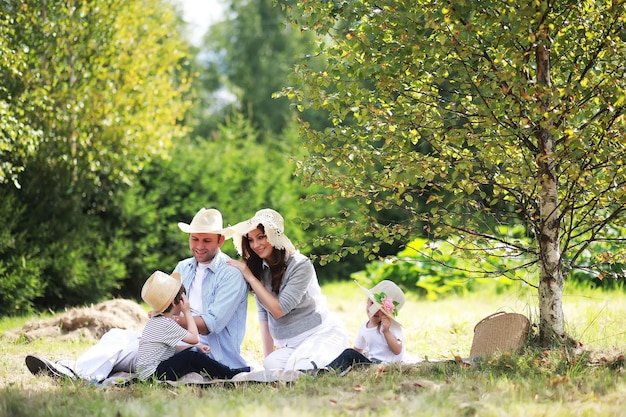 Famiglia felice con bambini che fanno picnic nel parco, genitori con bambini seduti sull'erba del giardino e che mangiano anguria all'aperto
