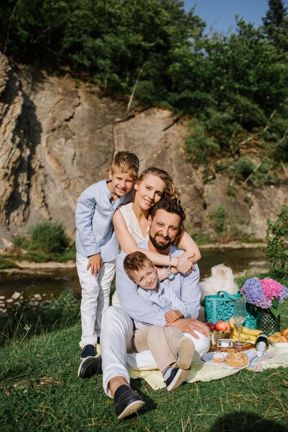 Famiglia felice con bambini durante un picnic nel parco nazionale in riva al fiume