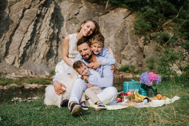 Famiglia felice con bambini durante un picnic nel parco nazionale in riva al fiume